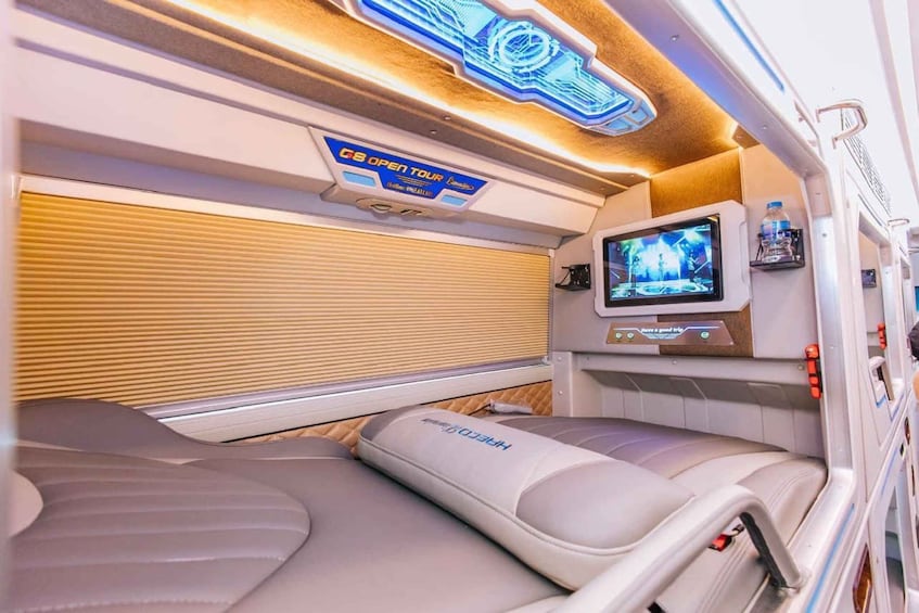 A train interior with a 'GS Open Tour' sign, a television screen, and reclining seats. 1