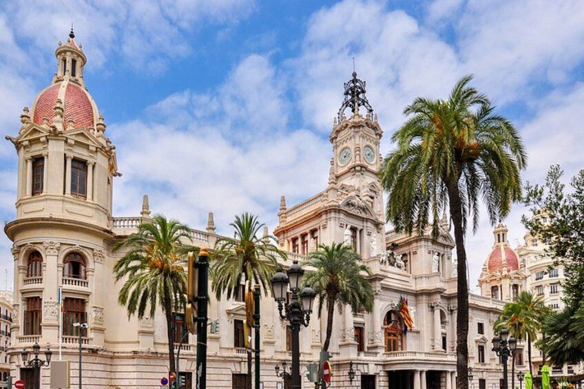 A historic building with a red dome, a clock tower, and palm trees. 3