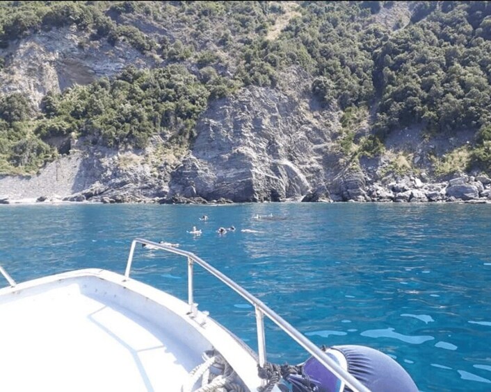 A boat on calm blue water with rocky cliffs in the background. 3