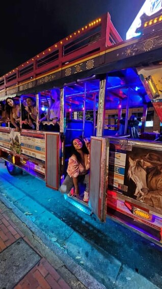 A brightly lit, colorful bus with passengers seated inside. 5