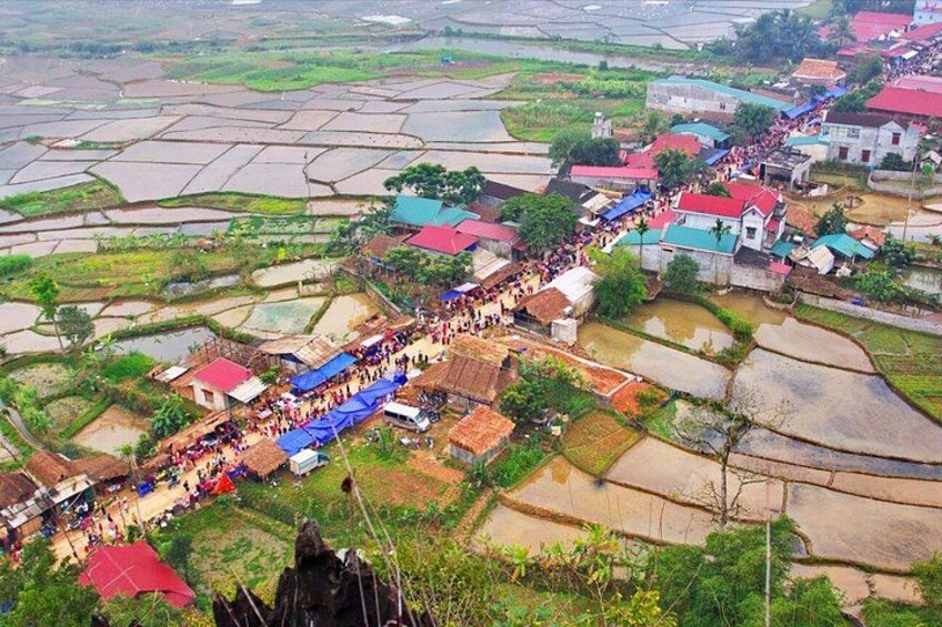 A rural village with terraced fields, houses with red roofs, and a crowd of people gathered in the center. 4