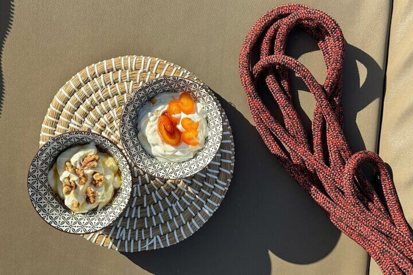 Two bowls of food on a woven plate, a red rope, and a shadow on a beige surface. 4