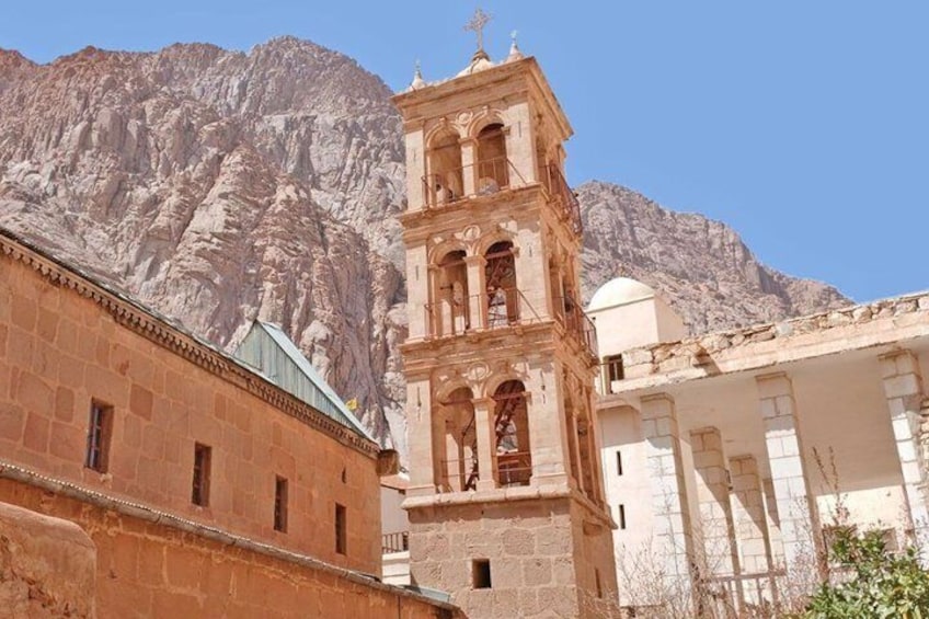 A historic church with a bell tower, set against a mountainous backdrop. 3