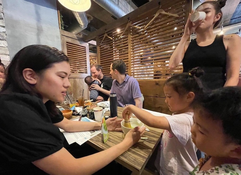 A group of people dining at a restaurant with wooden slats and a brick wall in the background. 1
