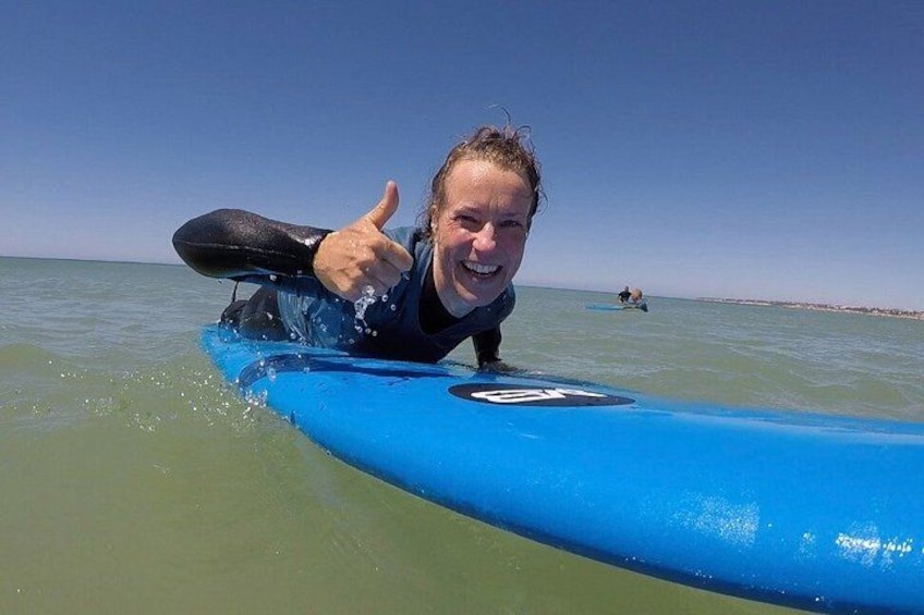 A person on a blue surfboard in the ocean with another person in the background. 1