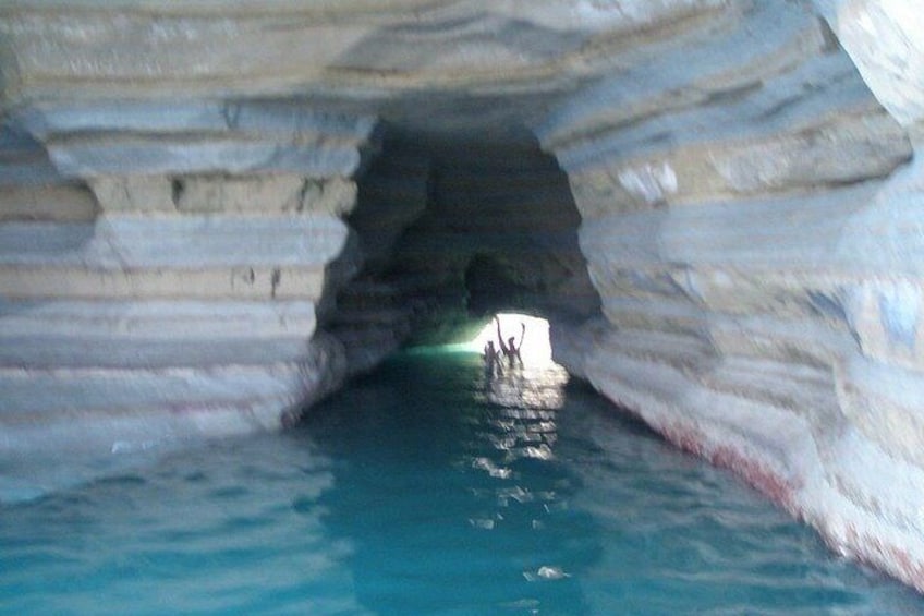 A cave with layered rock formations and a pool of water. 5