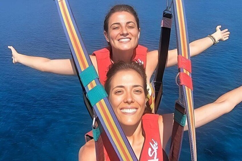Two people on a boat with their arms outstretched, wearing life jackets. 1