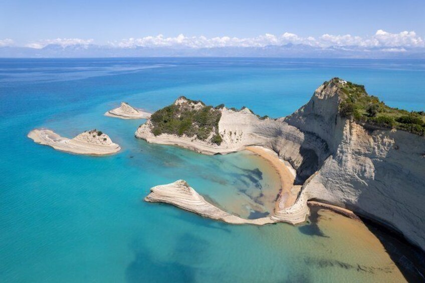 A coastal landscape with clear turquoise waters, white sandy beaches, and rocky outcrops. 5