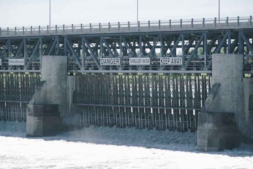 A bridge with warning signs, metal railings, and concrete supports. 4