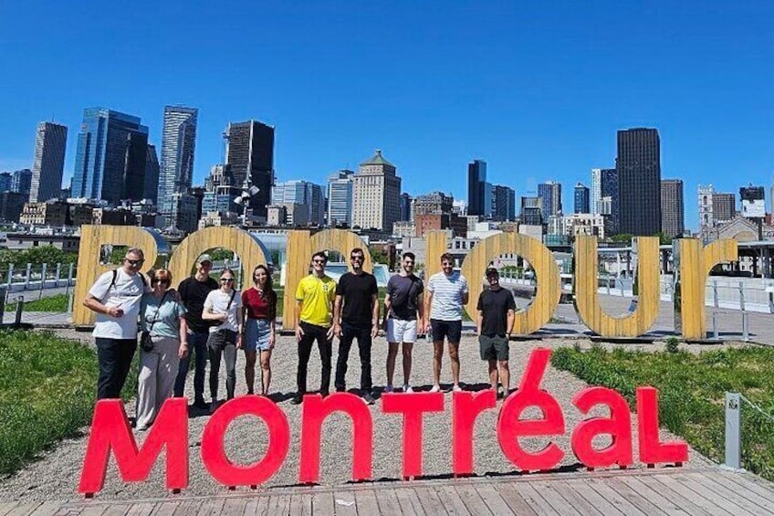 A group of people standing in front of a large sign with 'Montreal' written on it. 4