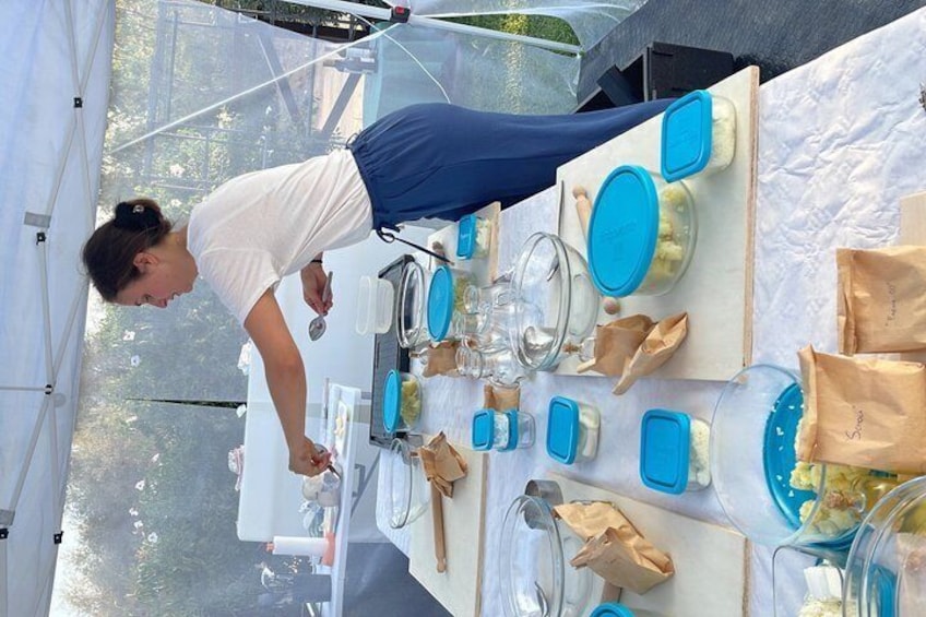 A person preparing food at an outdoor event with tables set with blue and white plates, bowls, and utensils. 3