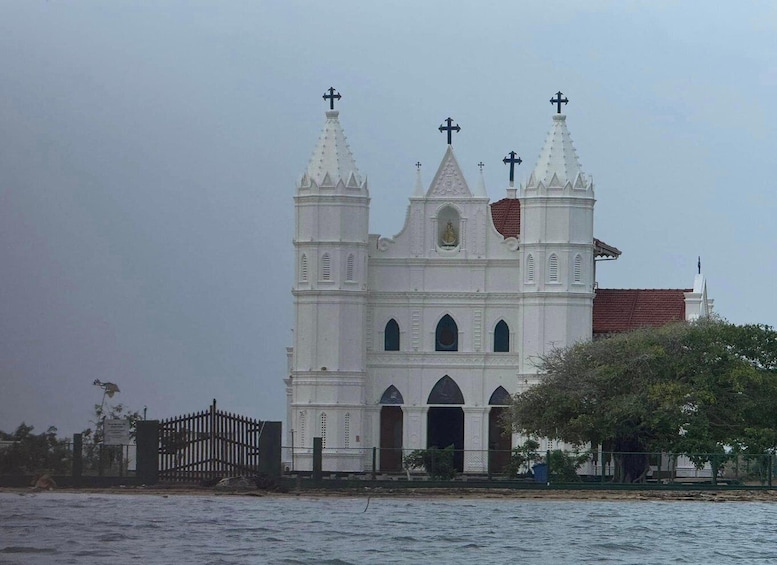 A white church with two towers and crosses, a red roof, and a fence in front. 1