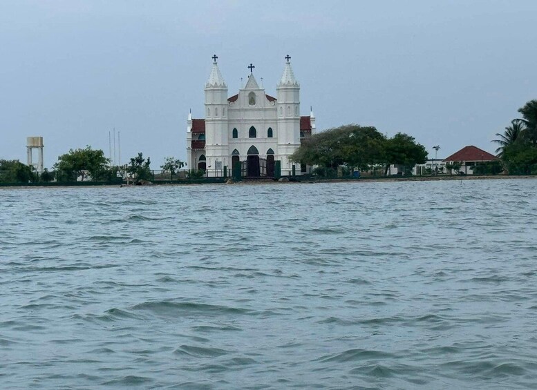 A white church with three towers and crosses, surrounded by calm water and greenery. 4