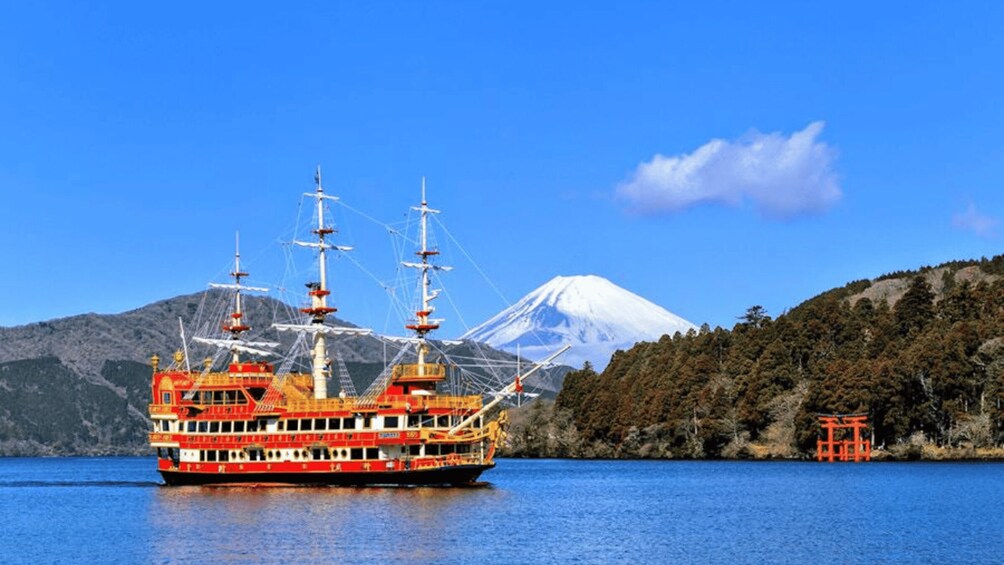 A red and white boat on a calm lake with a snow-capped mountain in the background. 5