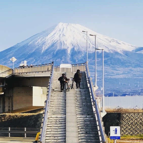 A snowy mountain with a bridge and people walking and biking. 2