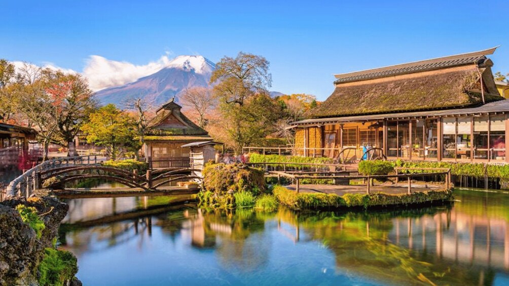 A traditional Japanese garden with a bridge, pond, and buildings. 1