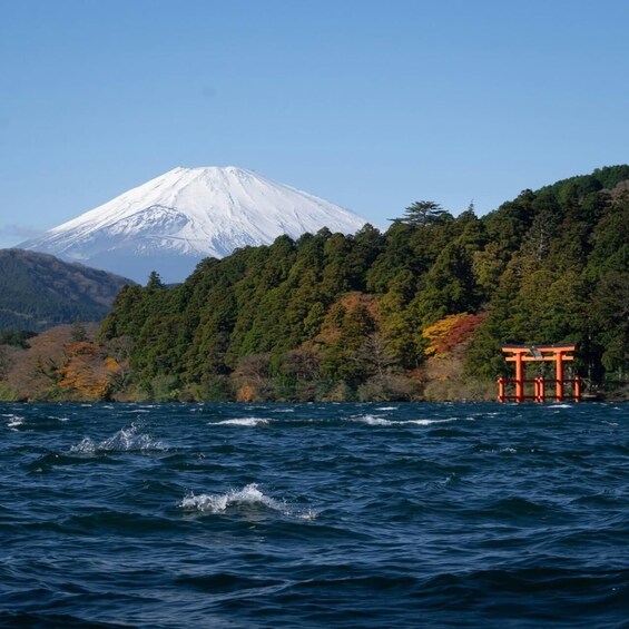 A snow-capped mountain, a forested hill, and a traditional Japanese torii gate by the water. 3