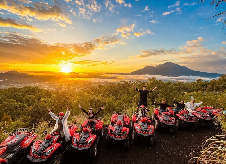 A group of people on ATVs with a sunset and mountains in the background. 1