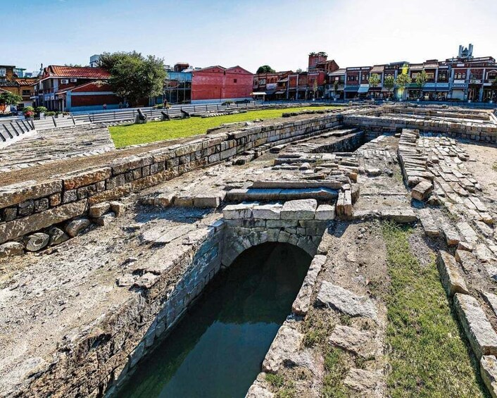 Ancient ruins with stone walls and a small bridge over a water channel. 3