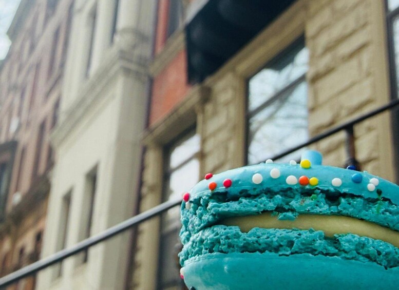 A blue cake with colorful sprinkles and frosting, in front of a building with large windows. 4