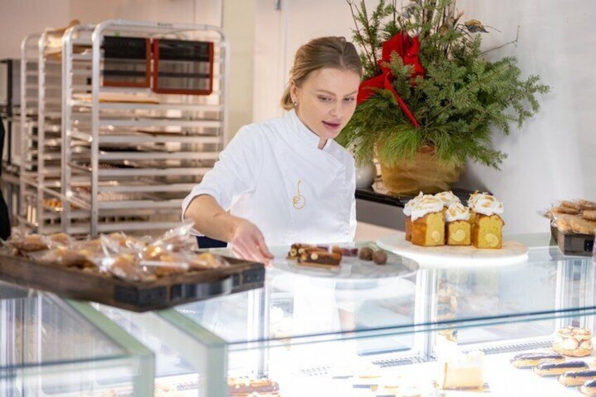 A bakery with a baker arranging pastries on a counter. 1