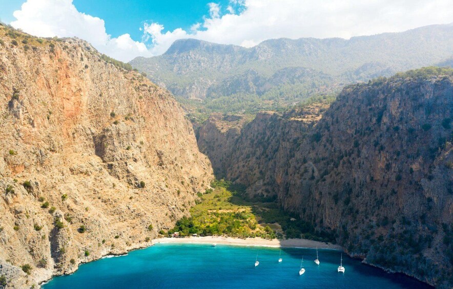 A coastal canyon with a beach and sailboats. 4