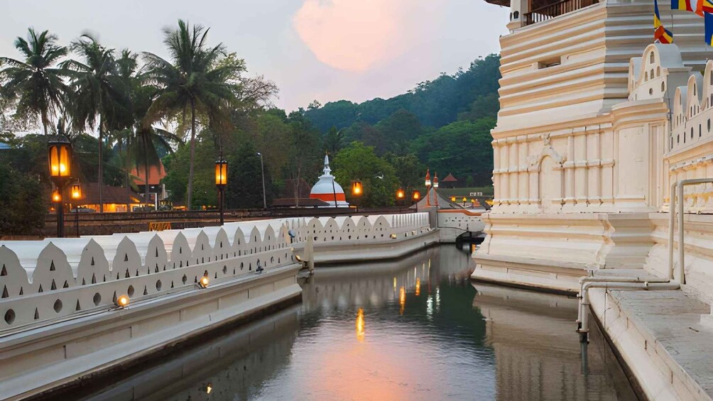 A temple with a reflection in a water channel, palm trees, and a sunset sky. 4