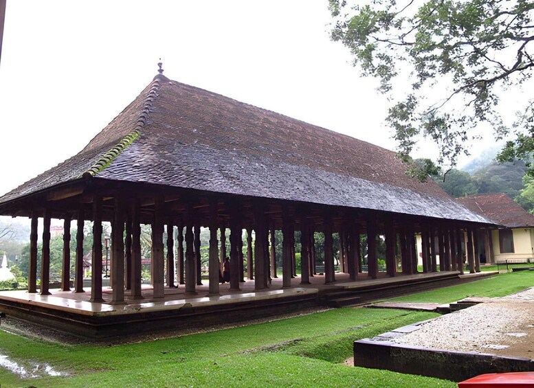 A traditional wooden pavilion with a tiled roof, surrounded by a well-maintained lawn and trees. 2