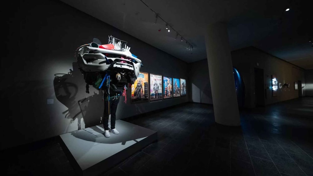 A mannequin in a dark room with a helmet and gear, surrounded by posters on the wall. 2