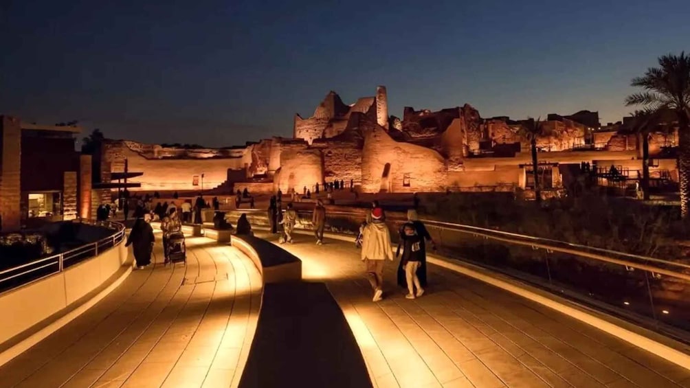 A nighttime view of a historical site with visitors walking on a wooden pathway. 3