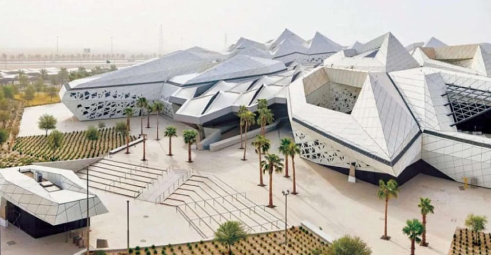A modern architectural complex with unique geometric structures and a landscaped area with palm trees. 1