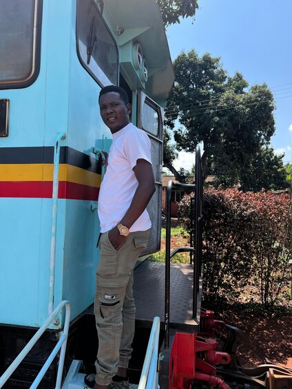 A person standing on the steps of a stationary train with a blue, red, and yellow stripe pattern. 2