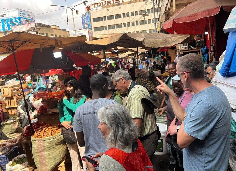 A bustling outdoor market with vendors and shoppers under makeshift canopies. 1