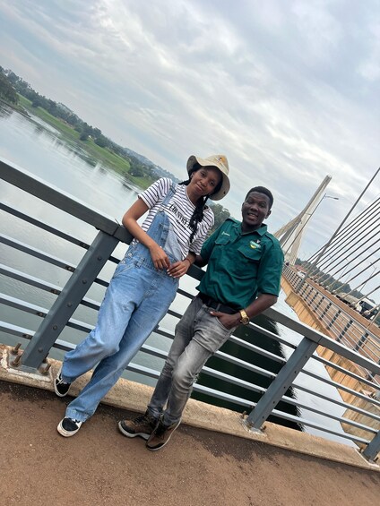 Two people standing on a bridge with a river and greenery in the background. 5