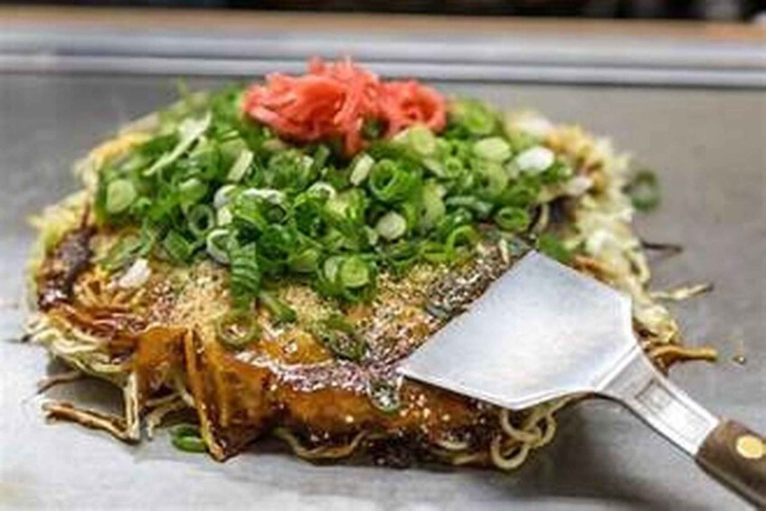A dish with noodles, green onions, and a red garnish on a plate. 2