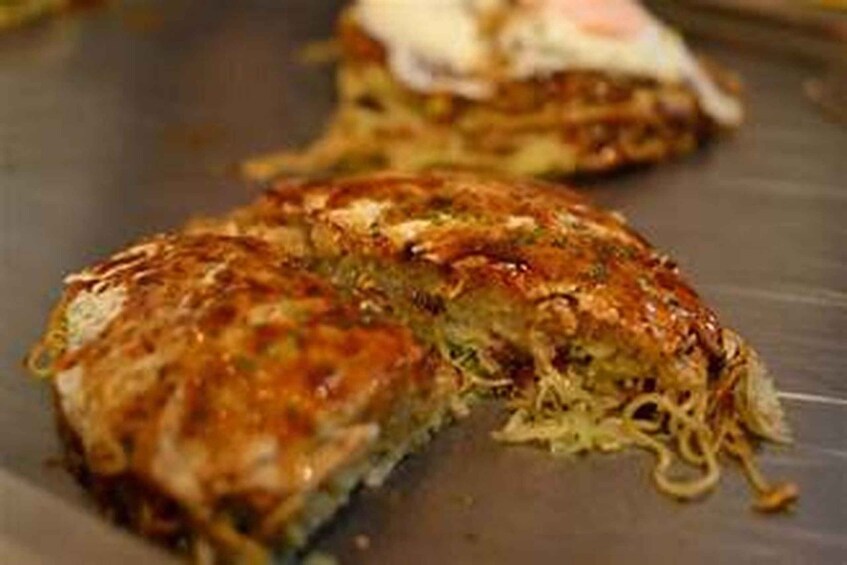 A close-up of a food item, possibly a pancake or fritter, with a golden-brown crust and visible green herbs. 4