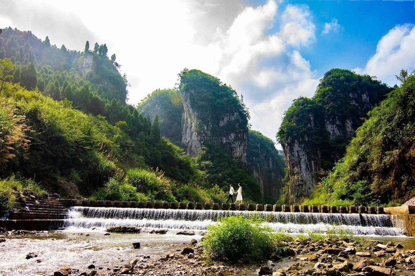 A waterfall cascading over stone steps, surrounded by lush greenery and rocky cliffs. 3