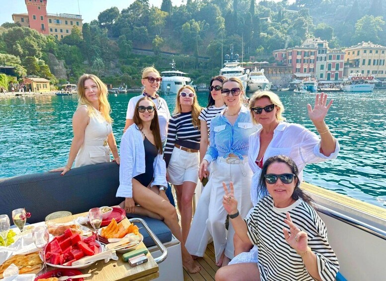 A group of people on a boat with a table of food and drinks, surrounded by water and buildings in the background. 1