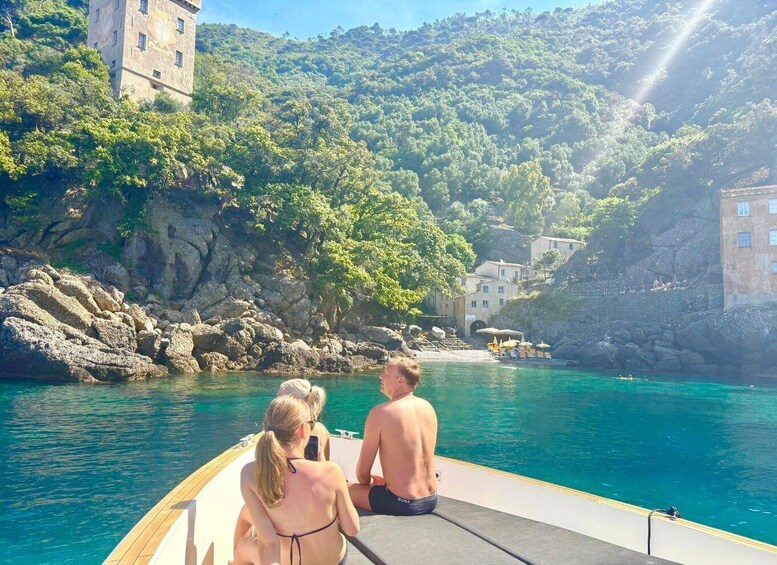 A boat on a turquoise sea with rocky cliffs and buildings in the background. 2