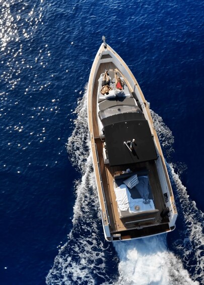 A speedboat with a person lying on the deck, another person standing, and a dog. 3