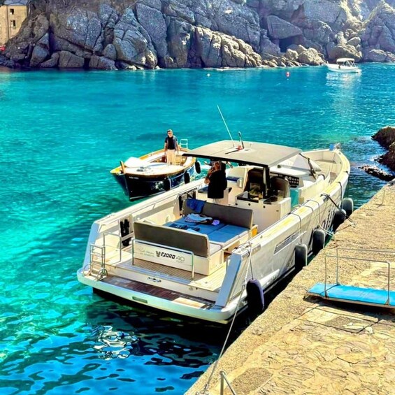 A boat docked at a pier with clear turquoise water and rocky cliffs in the background. 5