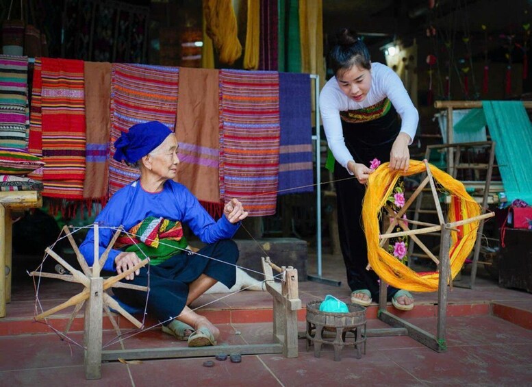 Two individuals engaged in weaving with traditional tools and colorful fabrics. 2