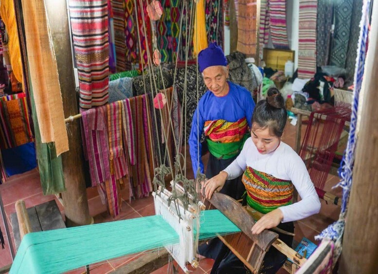 A person weaving with a loom, surrounded by colorful textiles. 5