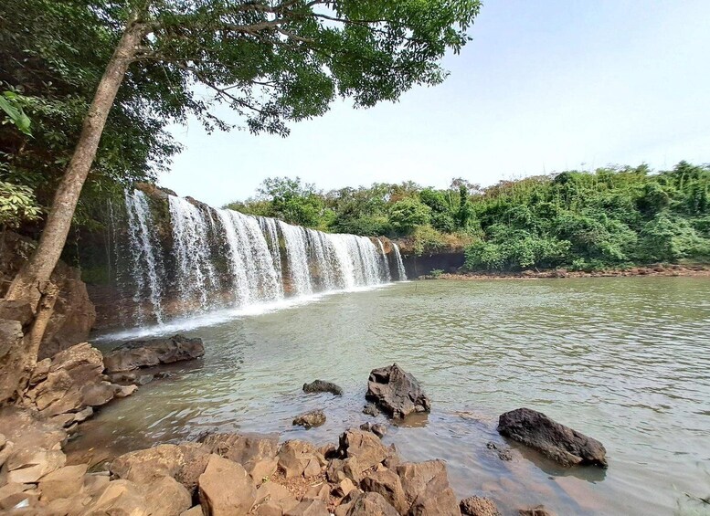 A waterfall cascading over rocks into a calm river, surrounded by lush greenery. 4