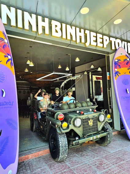 A jeep with military-style decorations parked in front of a building with a sign reading 'NINH BINH JEEP TOY'. 4