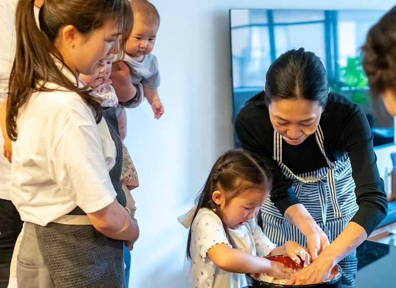 A woman in a striped apron assisting children with food preparation. 3