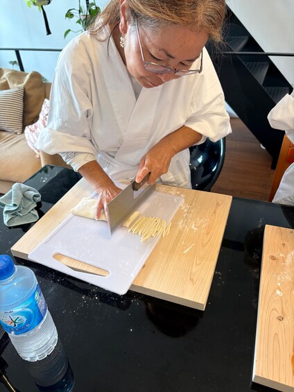 A person slicing pasta on a cutting board. 4