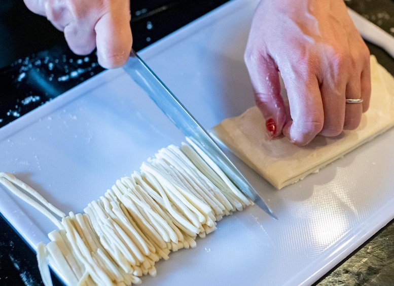 A person cutting a white, cylindrical object on a white cutting board. 4