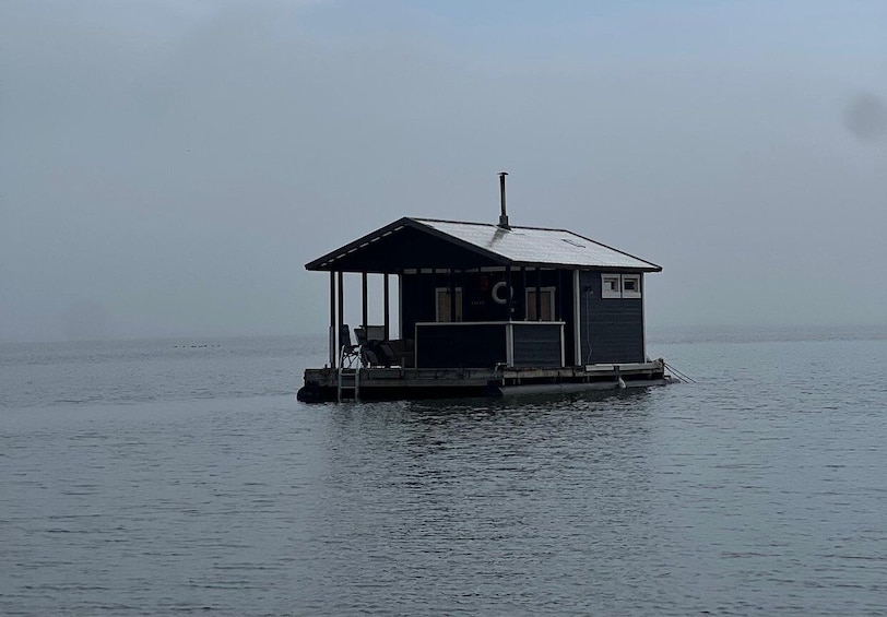 A small floating structure with a roof and a chimney, surrounded by calm water. 3