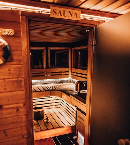 A sauna with wooden walls and benches, a sign labeled 'SAUNA', and a towel rack. 2